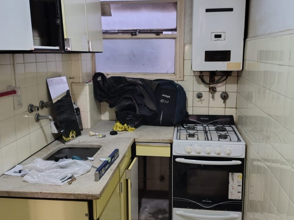 Cocina antigua antes de la reforma, muebles amarillos y calefón